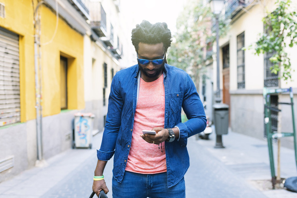 Африканський молодий чоловік використовує мобільний на вулиці
. - Фото, зображення