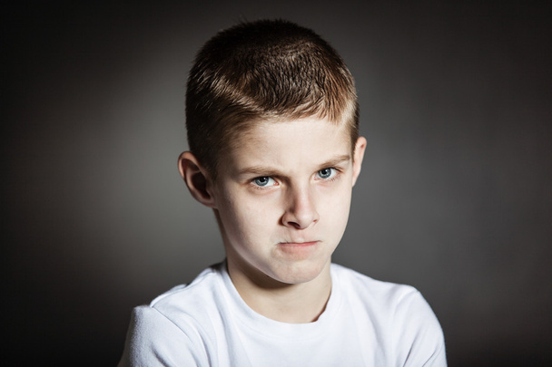 Wütendes männliches Kind posiert nachdenklich im dunklen Raum - Foto, Bild