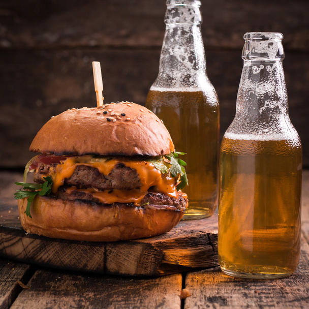 Fresh and tasty hamburger with a beer on a wooden table. - Foto, Imagen