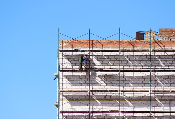 travailleurs sur les échafaudages construisent une maison de neuf étages à partir de blocs et de briques
. - Photo, image