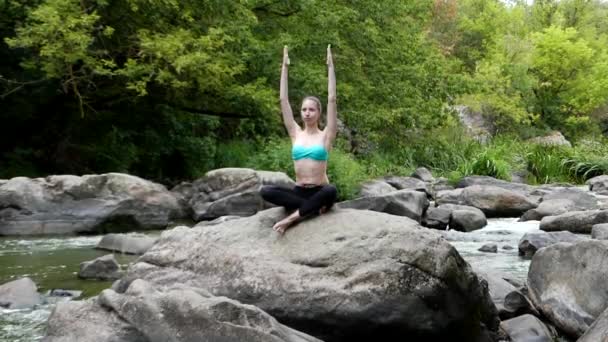山の川の中の岩の上に座って瞑想の美しい少女. - 映像、動画