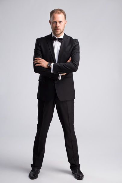 Handsome confident businessman in classic suit on gray background - Fotó, kép
