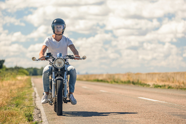 Junger Mann fährt mit Motorrad auf offener Straße - Foto, Bild