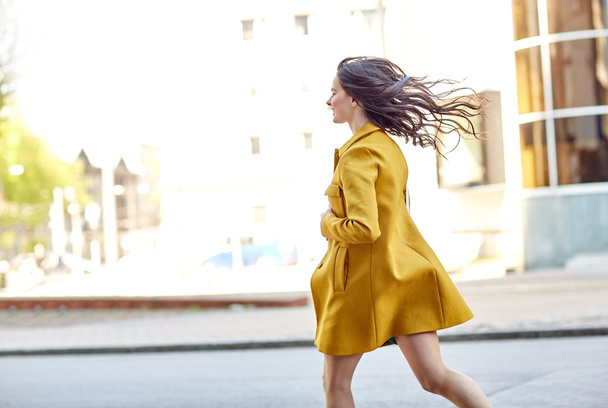 happy young woman running along on city street - 写真・画像