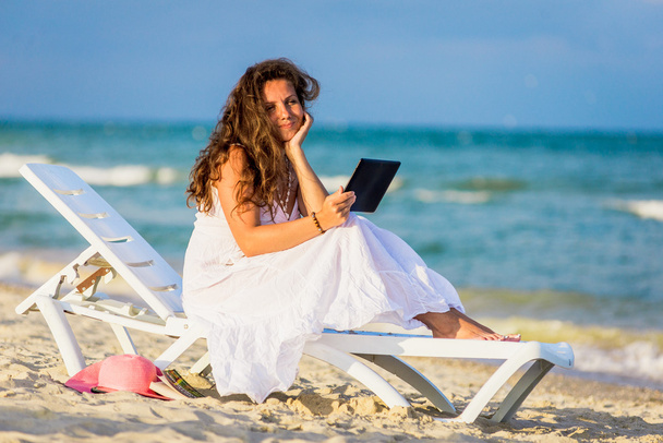 Jeune femme en chapeau avec tablette PC à la plage
 - Photo, image