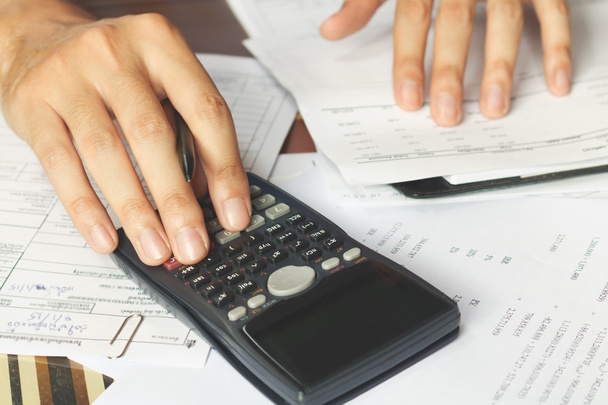 savings, finances, economy and office concept. Business people counting on calculator sitting at the table. Close up of hands and stationery, soft focus - Photo, Image