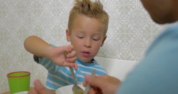 Ο πατέρας διδάσκει τον γιο να χρησιμοποιεί ένα κουτάλι κατά τη διάρκεια του φαγητού - Πλάνα, βίντεο