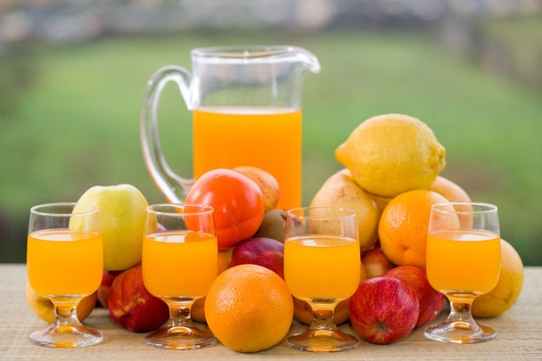 verres de jus d'orange et beaucoup de fruits sur la table en bois extérieure
 - Photo, image