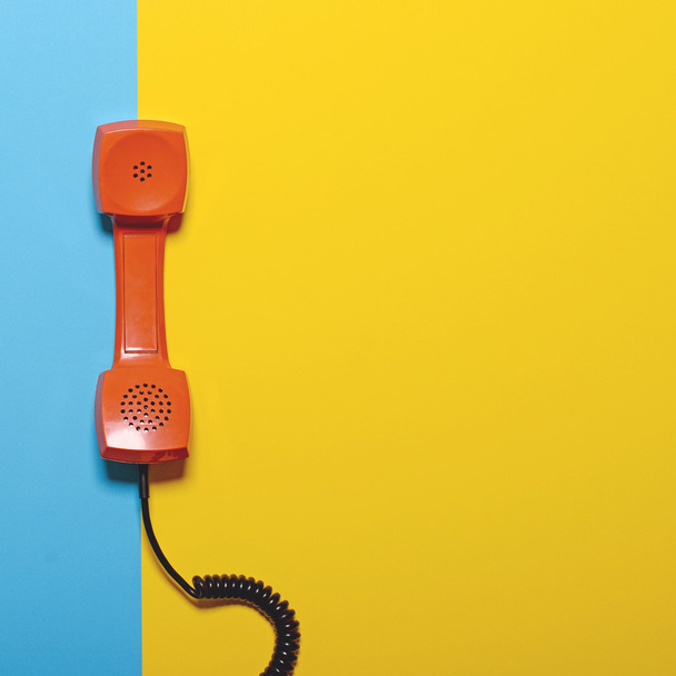 Retro orange telephone tube on striped blue and yellow backgroun - Fotoğraf, Görsel