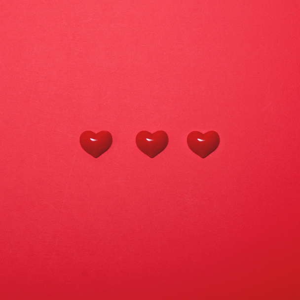 Three small hearts on red background - Minimal design - Φωτογραφία, εικόνα