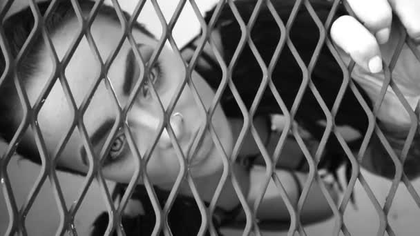 Nahaufnahme Porträt einer sinnlich schönen Engelsfrau, die im Käfig gefangen nach oben schaut - Schwarz-Weiß-Video - Filmmaterial, Video