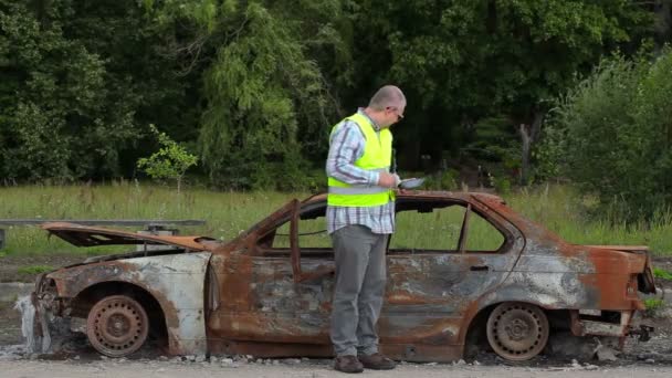 Inspector usando tableta PC cerca de los restos de coche en la carretera
 - Metraje, vídeo