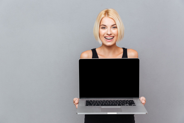 Happy cute young woman holding blank screen laptop - Фото, изображение