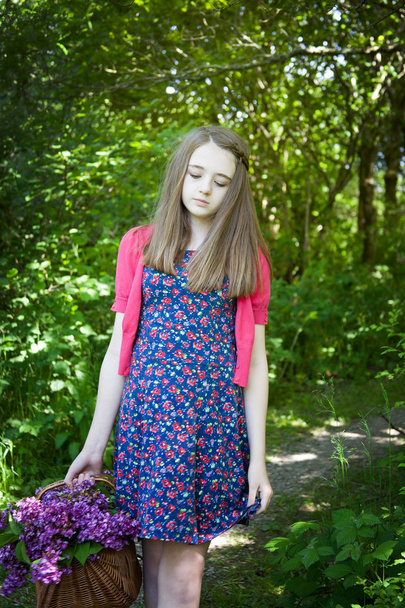 Beautiful teenage girl walking in woods with a basket of flowers - Fotoğraf, Görsel