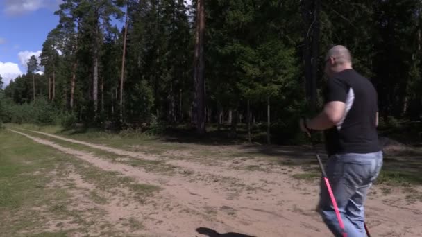 Wandelaar met wandelstokken weglopen op bos weg in 4k - Video