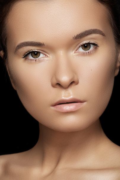 Spa, skincare, wellness, health & tan. Close-up portrait of beautiful female model face with purity health skin & light make-up on black background. - Photo, image