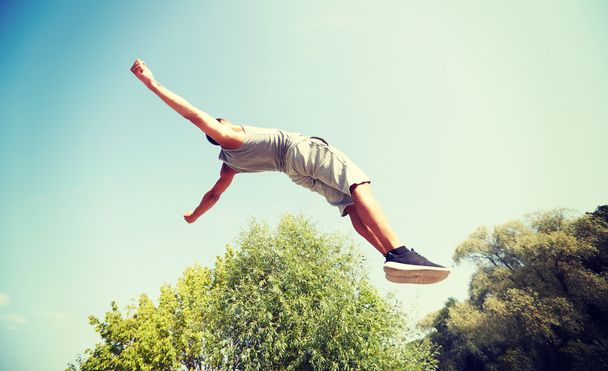 urheilullinen nuori mies hyppää kesäpuistossa
 - Valokuva, kuva