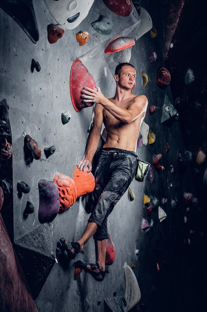 Man op een indoor klimwand klimmen - Foto, afbeelding
