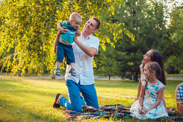 Young happy family of four on picnic in the park - Foto, immagini
