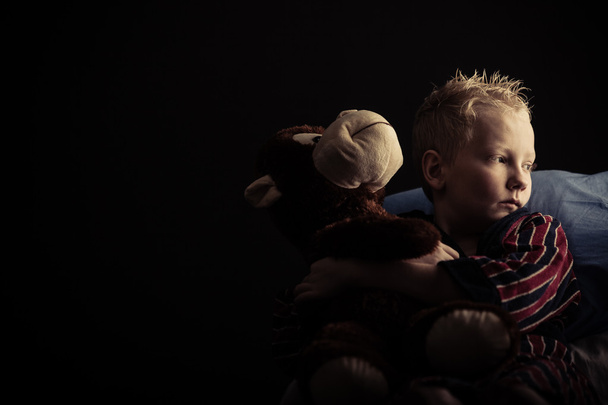Серьезный маленький мальчик сидит с плюшевой игрушкой
 - Фото, изображение