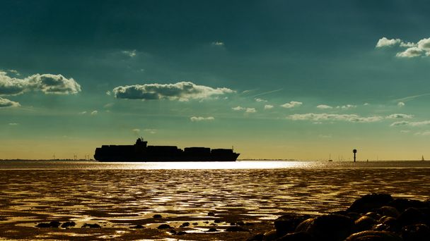 Silueta del buque contenedor contra la puesta del sol
 - Foto, Imagen