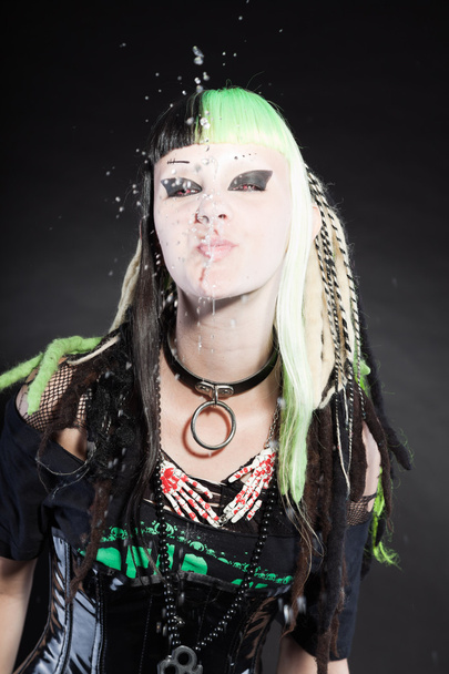 Cyber punk girl with green blond hair and red eyes isolated on black background. Spitting water. Expressive face. Studio shot. - Photo, Image