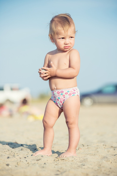 Lindo bebé jugando con juguetes en la playa de arena cerca del mar
. - Foto, Imagen
