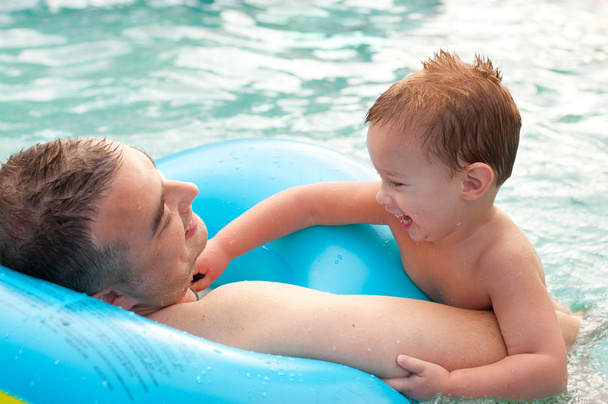 Father and his son having fun in the swimming pool on beautiful summer day - Photo, Image