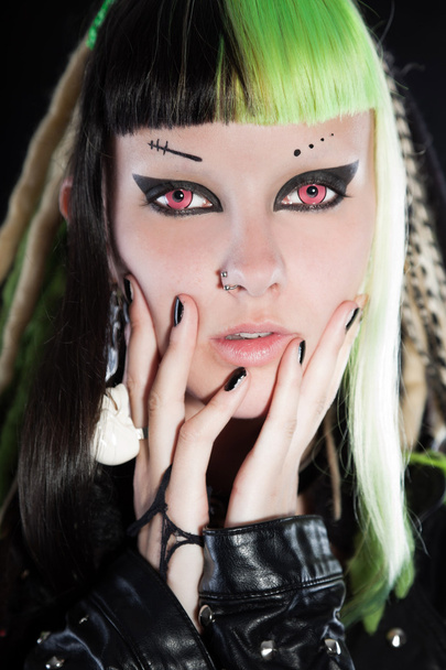 Chica cyber punk con cabello rubio verde y ojos rojos aislados sobre fondo negro. Cara expresiva. Captura de estudio
. - Foto, imagen