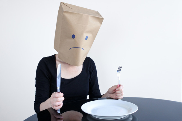 Anonieme triest vrouw met lege plat zitten aan de tafel alleen - Foto, afbeelding