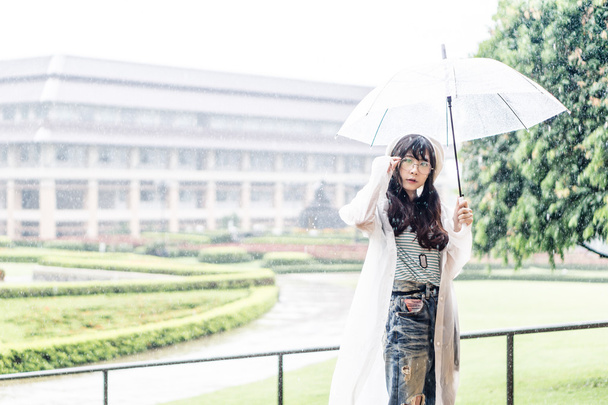 charmante asiatische Mädchen mit Regenschirm und Regenmantel  - Foto, Bild