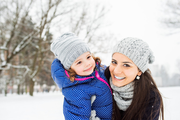 Mother with her daughter hugging outside in winter nature - Foto, imagen