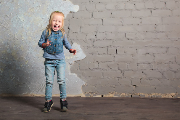 Erittäin onnellinen pieni tyttö tanssii, hyppää, hymyilee ja poseeraa
 - Valokuva, kuva