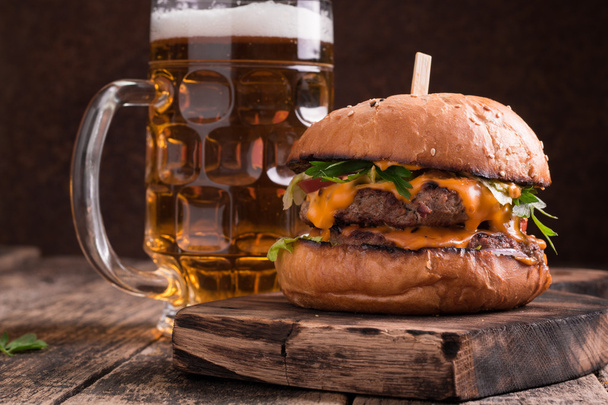 Fresh and tasty hamburger with a beer on a wooden table. - Foto, Imagem