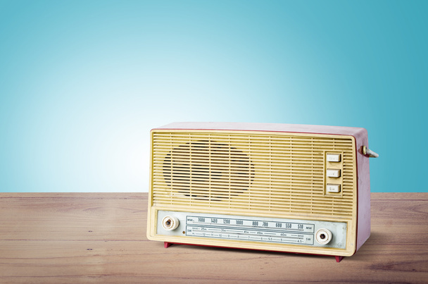 Old dusty radio from 1970 on wooden table with blue background. - Photo, Image