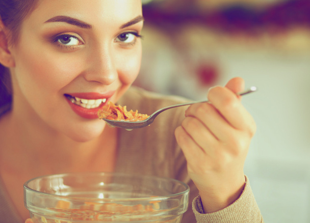 Усміхнена приваблива жінка снідає в інтер'єрі кухні
 - Фото, зображення