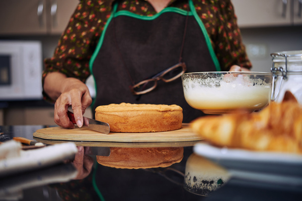 Женщина готова покрыть торт сливками
 - Фото, изображение