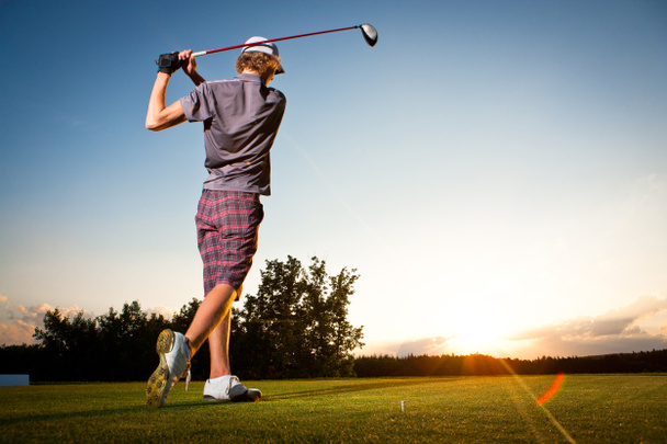 男子ゴルフ プレーヤー ゴルフ ボール ティー ボックスから美しい夕日をティーオフ - 写真・画像