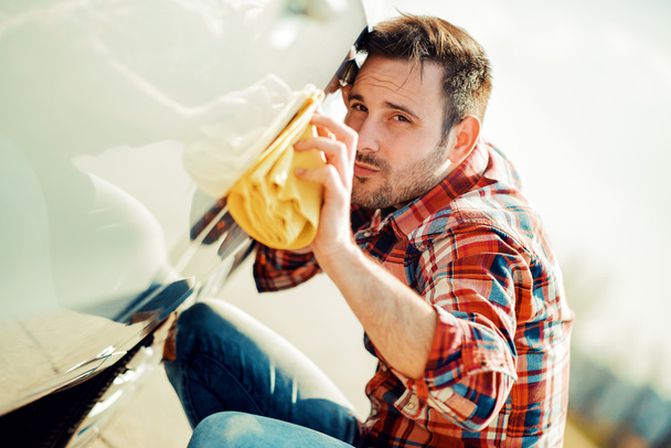 jonge man zijn auto schoonmaken  - Foto, afbeelding
