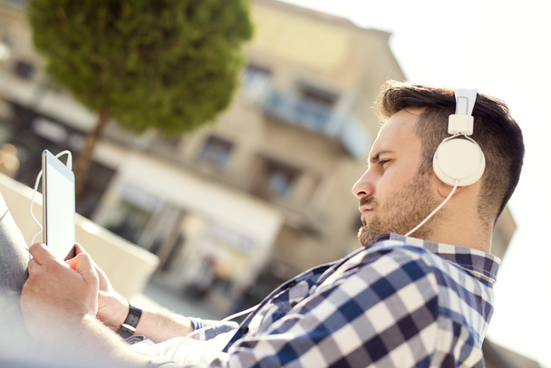 Gros plan d'un jeune homme assis à l'extérieur à écouter de la musique
 - Photo, image