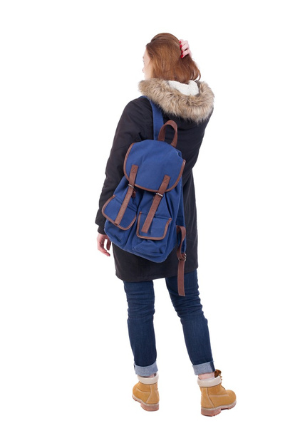 Back view woman in winter jacket  with a backpack looking up - 写真・画像