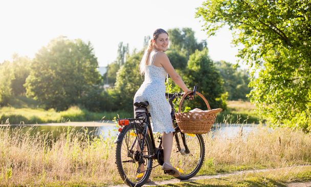İçinde sıcak su, nehir kıyısında bir bisiklet sürme güzel kadın - Fotoğraf, Görsel