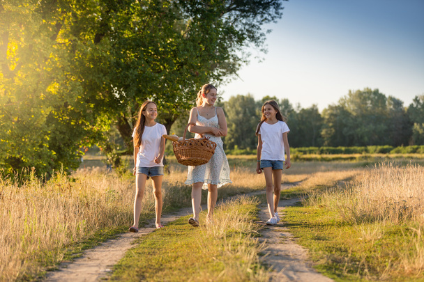 Güzel anne iki kızıyla birlikte piknik için yürüyüş  - Fotoğraf, Görsel
