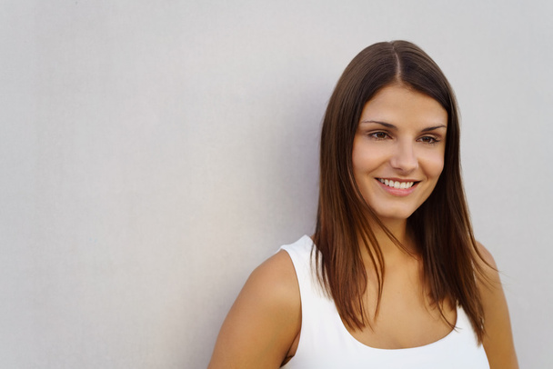 Mujer sonriente alegre en blanco al lado de la pared
 - Foto, imagen