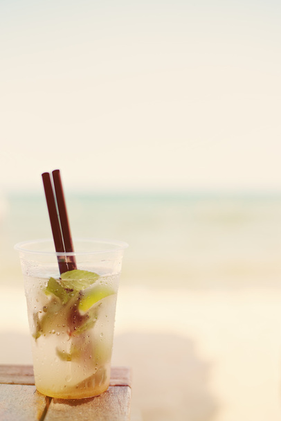 Mojito cocktail on the beach, blurred beach background. Sun, sun haze, glare - Photo, Image