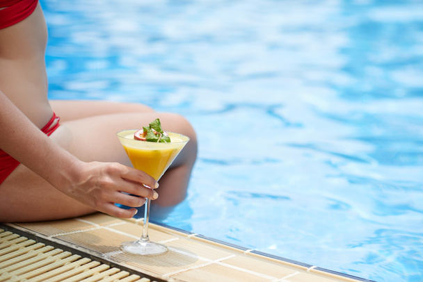 жінка сидить біля басейну з коктейлем
 - Фото, зображення