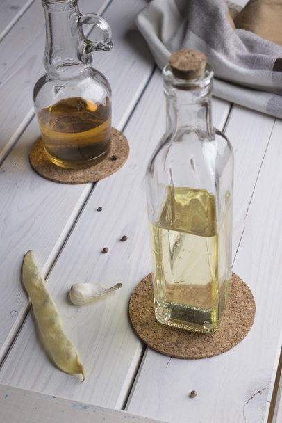 Transparent bottles with oil and vinegar on white wooden table. - 写真・画像