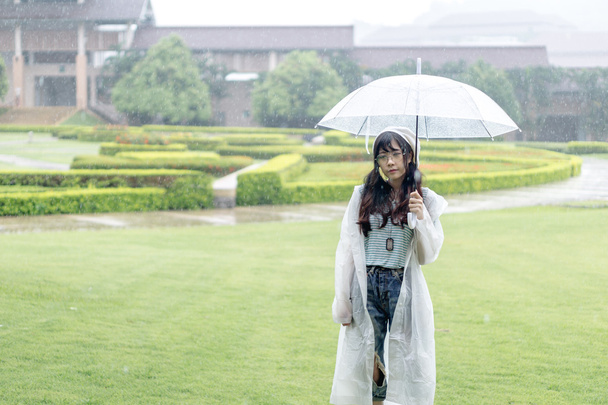 Menina asiática encantadora com guarda-chuva e capa de chuva
  - Foto, Imagem