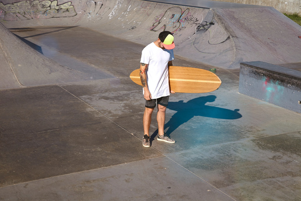 Unrecognizable tattooed skater with longboard - Foto, imagen