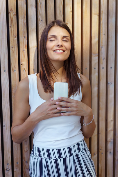 Woman with satisfied expression using phone - Φωτογραφία, εικόνα